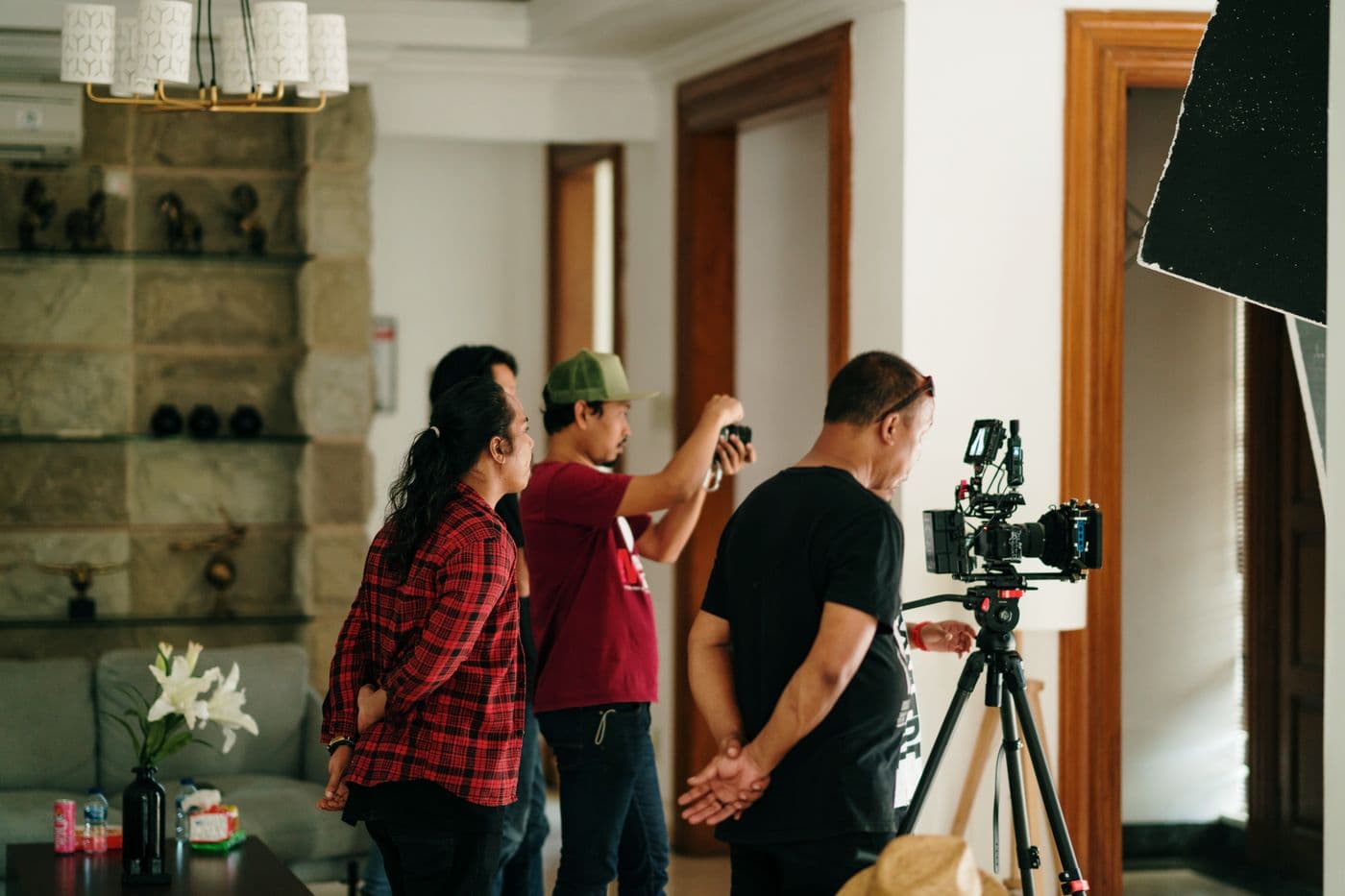 Une équipe de tournage prépare une caméra sur pied dans un décor intérieur lumineux