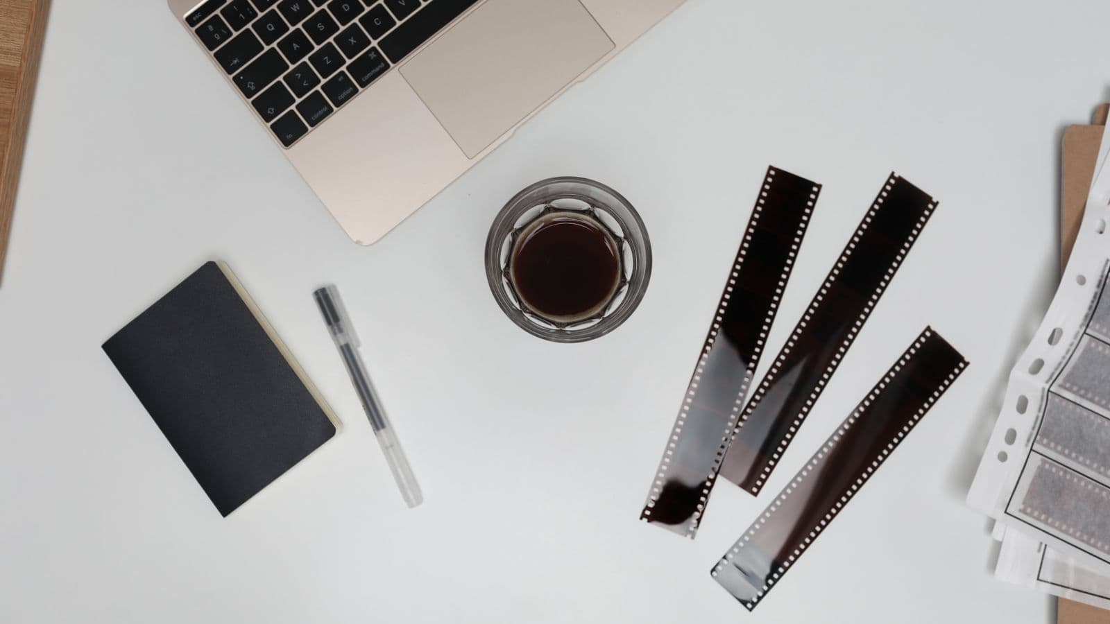 Bureau clair avec un ordinateur portable, un carnet, un stylo et des bandes de pellicule
