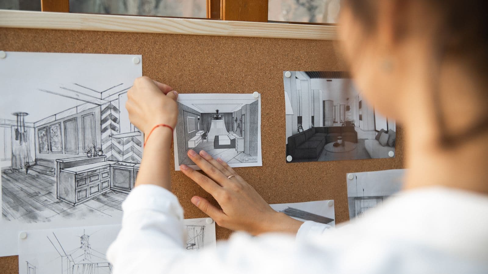 Personne épinglant des croquis et des références visuelles sur un panneau de liège