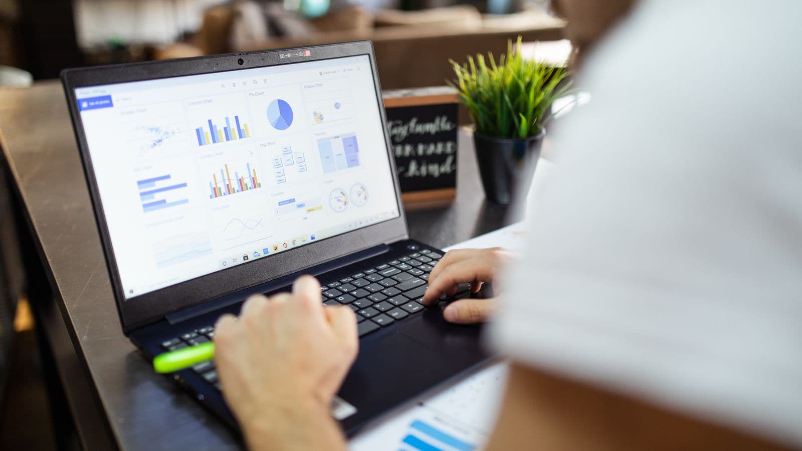 Une personne travaille sur un tableur affiché sur l'écran d'un ordinateur portable posé sur un bureau