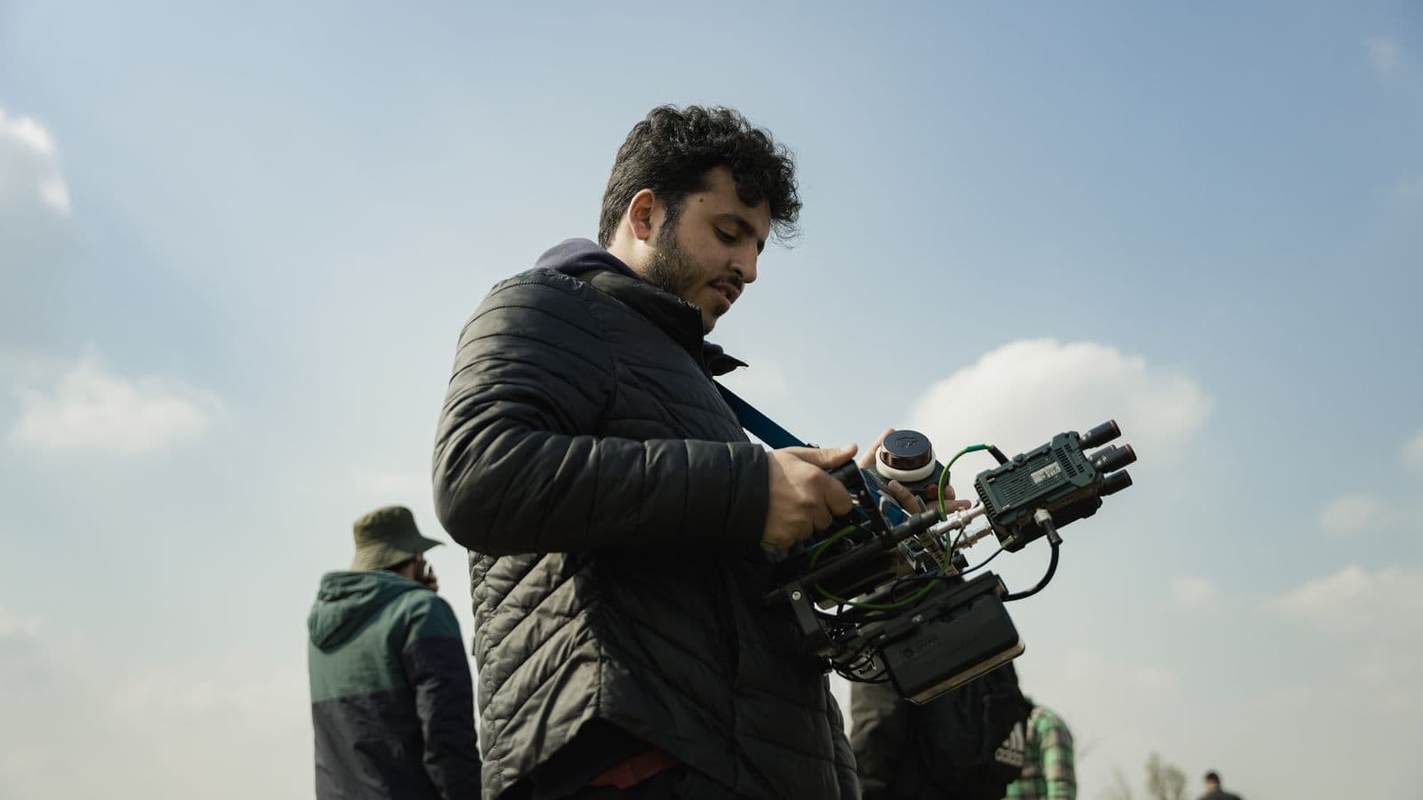 A camera operator adjusting a rig on an exterior location during a shoot day